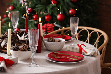 Dining table with Christmas setting and burning candles in room, closeup