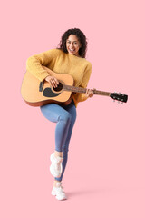 Obraz premium Young African-American woman playing acoustic guitar on pink background