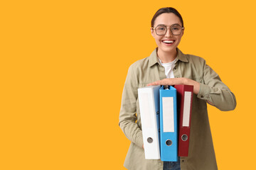 Young businesswoman with document folders on yellow background