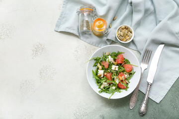 Bowl with healthy vegetable salad, spices and cutlery on grey grunge background