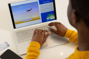 Booking holiday travel online, African american man using laptop at home, planning vacation