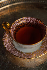 cup of black ceylon tea in pink and gold pattern teacup and saucer sitting on silver tray