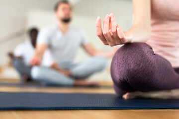 Closeup of female hand with fingers folded in mudra. Hand lying on knee while woman sitting in yoga...
