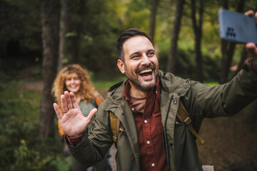 Adult man hiker take a self portrait while his wife stand behind him