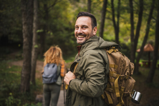 Adult man hiker stamp through the fores behind his wife