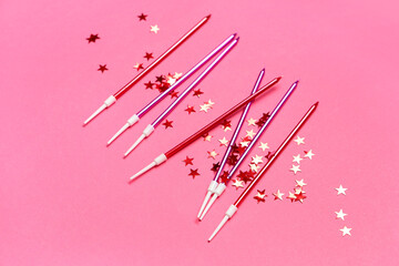 Many Birthday candles and confetti on pink background