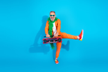 Full size photo of funny trendy aged man dancing hold boombox wear orange costume isolated on blue...