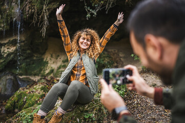husband take a photo of wife backpacker in front cave in the forest