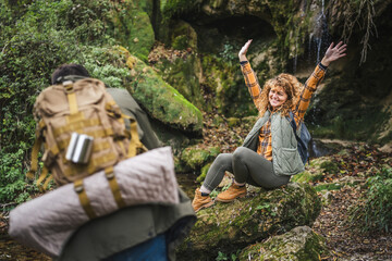 husband take a photo of wife backpacker in front cave in the forest