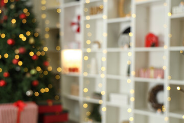 Shelving unit with decor, Christmas tree and gifts in living room, blurred view