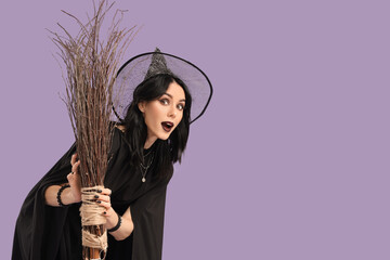 Beautiful young shocked woman dressed as witch for Halloween with broom on purple background
