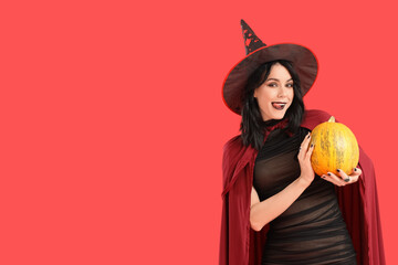 Beautiful young happy woman dressed as witch for Halloween with pumpkin on red background