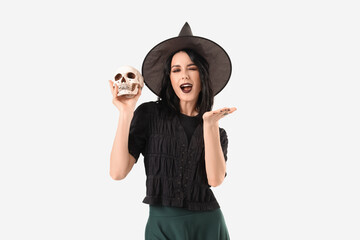 Beautiful young shocked woman dressed as witch for Halloween with human skull isolated on white...