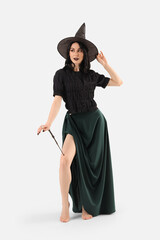 Beautiful young woman dressed as witch for Halloween with magic wand isolated on white background
