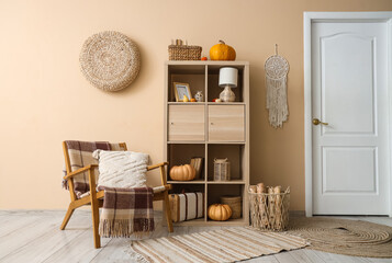 Armchair and shelf unit near beige wall in interior of living room