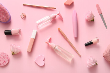 Composition with cosmetics, makeup accessories and flowers on pink background