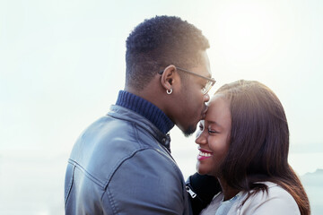 Forehead kiss, happy and black couple in nature for bonding, relationship and relax together outdoors. Love, morning and man and woman with embrace for affection, romance and dating on weekend