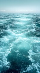 Fototapeta premium A serene view of deep turquoise ocean water with gentle waves, creating a tranquil atmosphere. The sunlight reflects beautifully on the surface, enhancing the soothing mood.