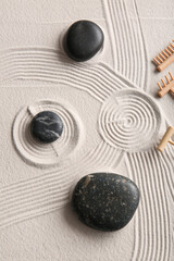 Black stones and small rakes on light sand with lines. Zen concept