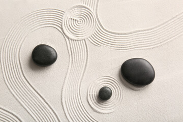 Black stones on light sand with lines in Japanese rock garden. Zen concept
