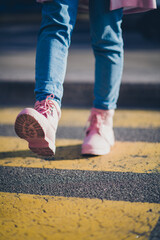 Cropped vertical photo of young girl pink boots advert walk pedestrian crossing street outdoors