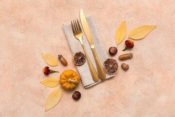 Stylish cutlery with autumn leaves, beautiful flowers, fresh pumpkin and slices of dried orange on beige background