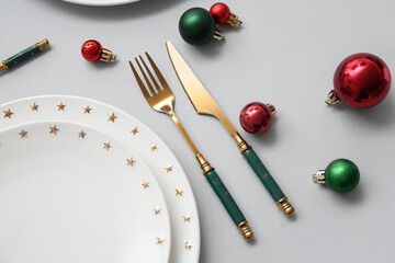 Beautiful table setting with Christmas balls on grey background