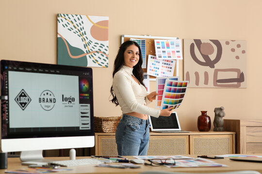 Young female graphic designer with color palettes and computer in office