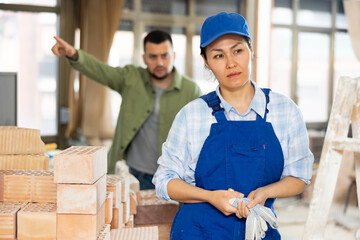 Depressed asian woman builder offended by construction manager shouting in background.