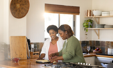 African american female friends preparing thanksgiving pie together in cozy kitchen, at home