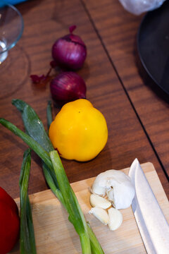 Fresh vegetables and garlic on cutting board with knife in kitchen, at home
