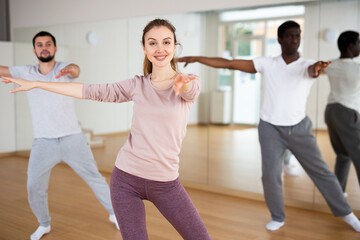 Fototapeta premium Woman and men dancing in fitness studio. Aerobic dance group practice.