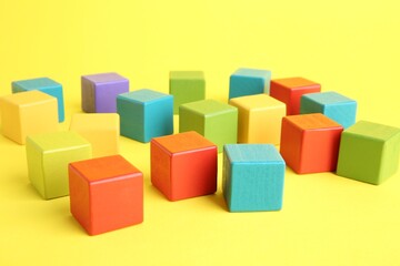 Many wooden colorful cubes on yellow background