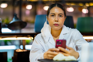 A focused scientist wearing a mask and goggles observes samples through a microscope in a lab. Surrounded by glassware, the scene highlights detailed research and scientific exploration.
