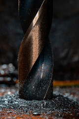 detailed macro of a drill bit drilling into metal with filings