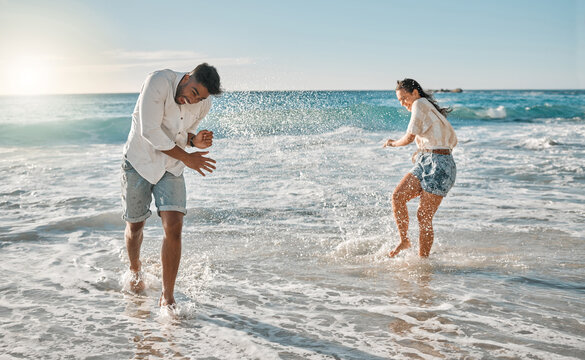 Playing, splash or happy couple hug at beach for love on vacation, valentines day or holiday in Spain. Kick, relationship and people in water for bonding together for trust or romantic trip at ocean