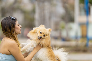 Woman holding a pomeranian dog in the park