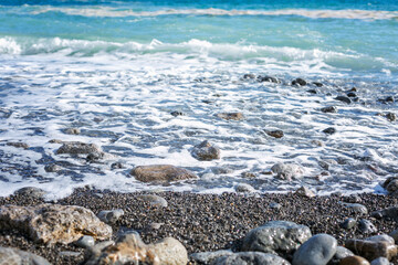 Foamy sea water on a black pebble beach. Space for text. Background. Close-up.