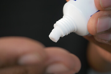 Applying cream from a tube onto a finger for skincare and beauty purposes is essential