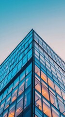 Fototapeta premium Modern glass building with warm interior lights at dusk