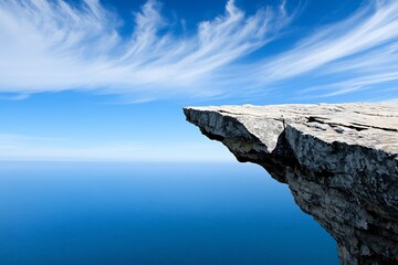 Dramatic rocky cliff edge overlooking vast blue ocean under clear sky : Generative AI