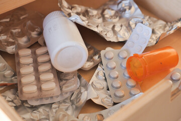 A Disordered Medicine Drawer Containing Various Pills, Packaging, and Additional Items