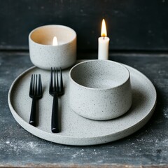 A minimalist dining setup with candles and utensils on a textured surface.