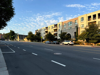 broad avenue in Los Angeles, California - urban cityscape - empty street, parked cars, apartment buildings and stores 