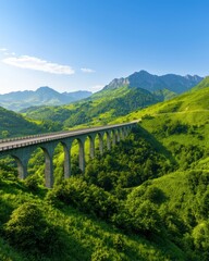 Naklejka premium Scenic railway bridge over lush green mountains under bright blue sky.