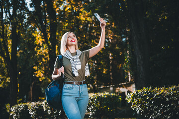 Photo of positive young blonde girl take selfie photo wear khaki outfit tied shoulders sweater walk park sunny spring weather outside