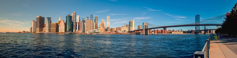 Naklejka premium DowntownManhattan Skyline with Brooklyn Bridge: A stunning view showcasing iconic skyscrapers and the historic bridge, beautifully illuminated at sunset, reflecting the vibrant energy of New York City