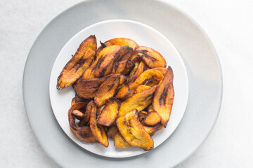 Overhead view of fried plantains on a white plate. Top view of fried ripe plantains on a plate