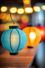 Obraz premium Blue Paper Lantern with Warm Glow: A close-up of a turquoise paper lantern, its warm glow illuminating the scene. The lantern hangs in a string of lights, creating a cozy and festive atmosphere.