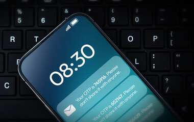 OTP message notification on mobile screen with laptop in the backdrop. One time password for secure verification of payment and accounts, background design with mobile screen